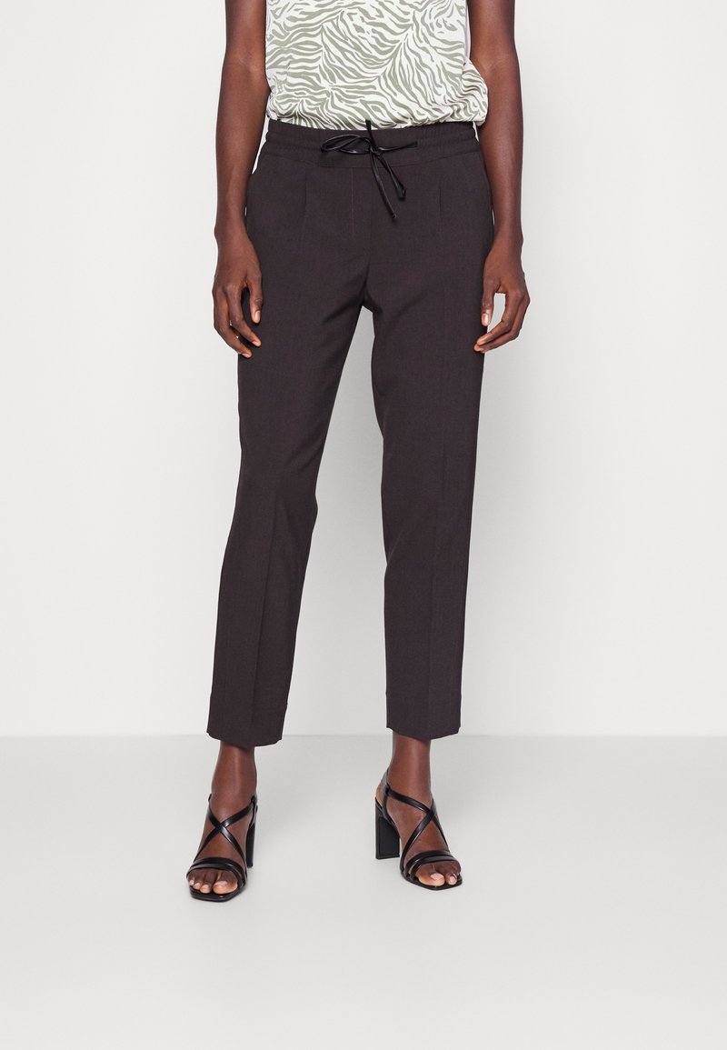 Svarta skräddarsydda byxor med dragsko i midjan, avsmalnande skärning, subtil textur och framfickor. Bärs med en grön mönstrad top och svarta högklackade sandaler.