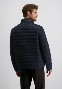 Marineblauwe gewatteerde pufferjas met een hoge kraag, horizontale stiksels en ritssluiting. Voorzien van elastische manchetten en een gladde textuur.