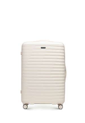 Walizka twarda w kolorze kremowym z poziomymi żebrowaniami, czterema obrotowymi kółkami, uchwytami na górze i z boku oraz etykietą marki WITTCHEN.