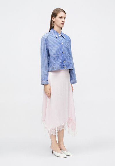 Τζιν μπουφάν με ρίγες μπλε και άσπρο, κοντό σχέδιο με δύο μπροστινές τσέπες, σε συνδυασμό με ανοιχτό ρόζ ασύμμετρη φούστα με δαντέλα στο τελείωμα. Λευκά mules.