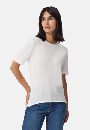 Weißes Baumwoll-T-Shirt mit kurzen Ärmeln, rundem Ausschnitt, leicht durchscheinendem Stoff und lässiger Passform, kombiniert mit blauen Jeans.