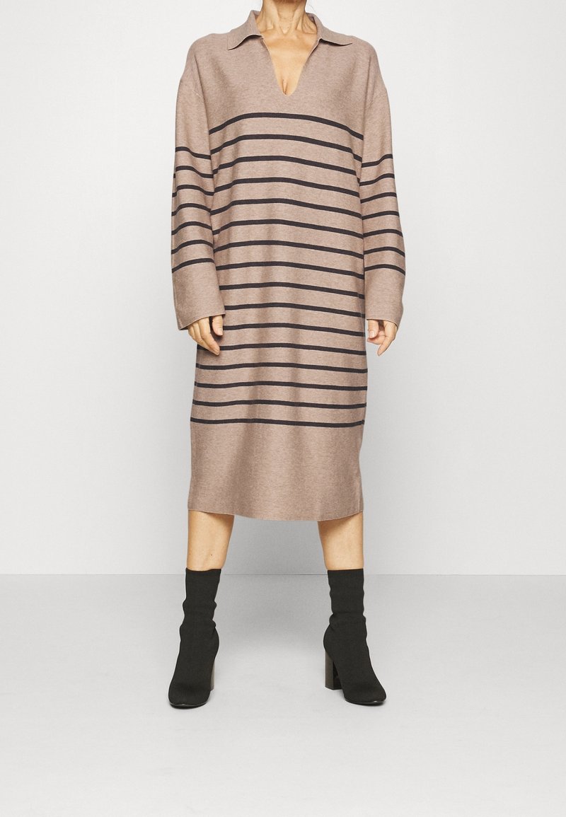 Šaty s dlouhým rukávem a výstřihem do V, vyrobené z měkké, béžové pleteniny s vodorovnými tmavě hnědými pruhy; délka ke kolenům s volnějším, rovně střihem.