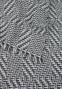 Leopardato bianco e nero con un motivo a zigzag, caratterizzato da bordi frangiati e una superficie texture.