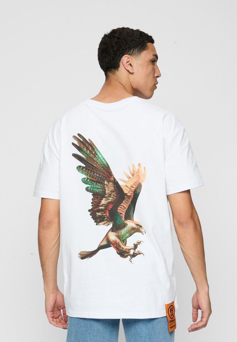 Hvid bomulds t-shirt med et stort, farverigt ørnegrafik på ryggen, med detaljerede fjer og et orange mærke ved kanten.