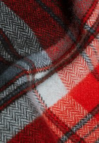 Tessuto di lana rosso e grigio con motivo a quadri e texture a spina di pesce, con quadrati alternati di rosso, bianco e grigio.