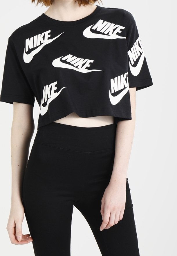 Svart kortärmad t-shirt i bomull med upprepade vita Nike-logotyper i olika orienteringar. Åtföljs av högmidjade svarta leggings.