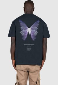 Black cotton t-shirt featuring a large purple and white butterfly graphic on the back. Crew neck and short sleeves, with text below the design.