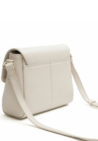 Petit sac bandoulière en cuir texturé écru avec une long bandoulière réglable et une fermeture à rabat, montré de dos et de côté.