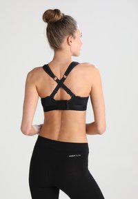 Soutien-gorge de sport noir avec un design à dos croisé, des bretelles ajustables et un fermoir à l'avant. Tissu lisse avec une finition mate.