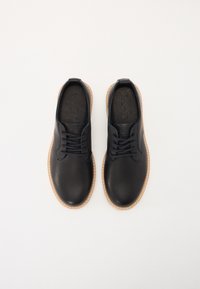 Black leather shoes featuring a smooth finish, lace-up design, and light brown rubber soles with contrast stitching.