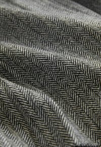 Auduma ar houndstooth rakstu melnā un pelēkā krāsā, ar mīkstu tekstūru un krītošu izskatu.