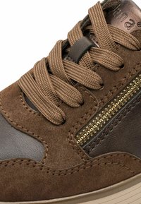Brown suede and leather sneaker with a textured surface, featuring brown laces and a golden zipper accent on the side.