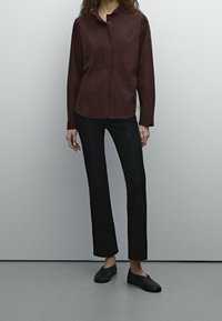 Chemise à manches longues en bourgogne, avec un tissu texturé, associée à un pantalon noir  à jambe droite et à des chaussures noires à enfiler simples.