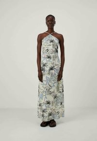 Maxi φόρεμα με λουράκι στο λαιμό, λουλουδάτο και τροπικό σχέδιο σε παστέλ αποχρώσεις. Κατασκευασμένο από ελαφρύ ύφασμα με κομψή σιλουέτα.