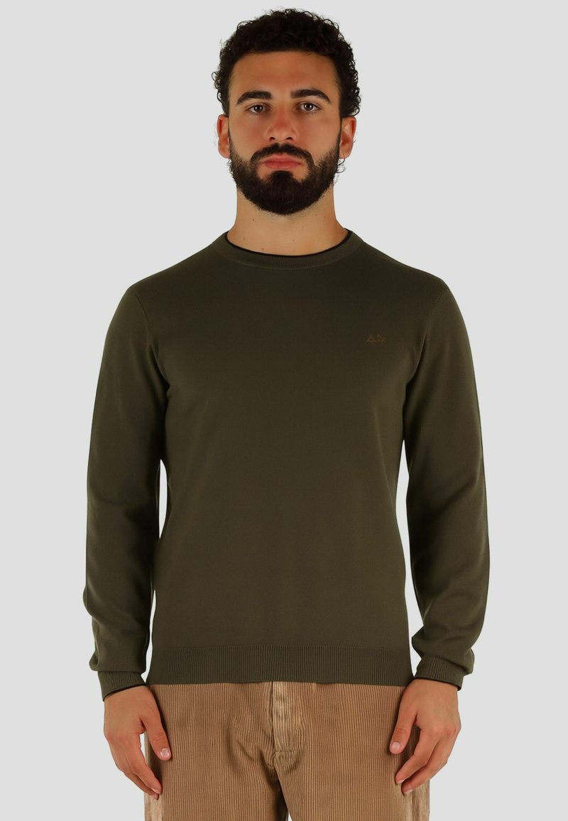 Pull col rond vert olive, manches longues, poignets et ourlet côtelés. Petit logo doré sur la poitrine gauche. Tissu lisse de poids moyen.