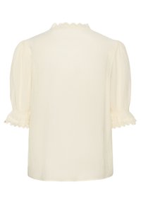 Kreemikas lühikeste varrukatega pluus tekstuurse kangaga, kaeluse ja varrukaäärte lainelise pitsiäärisega ning veidi puksitud varrukatega.