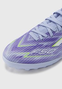 Purple and blue soccer cleat with a textured, striped design, featuring green accents and a logo reading "F50 SPARKFUSION."