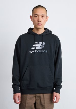 Felpa nera in tessuto felpato con tasca frontale, caratterizzata da un logo argento "new balance" stampato al centro. Design classico a pullover.