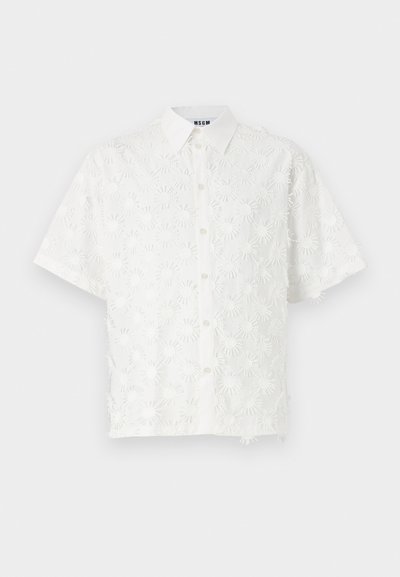 Hvit kortermet skjorte med knapper foran, prydet med intrikate blomsterbroderier og en lett teksturert overflate.