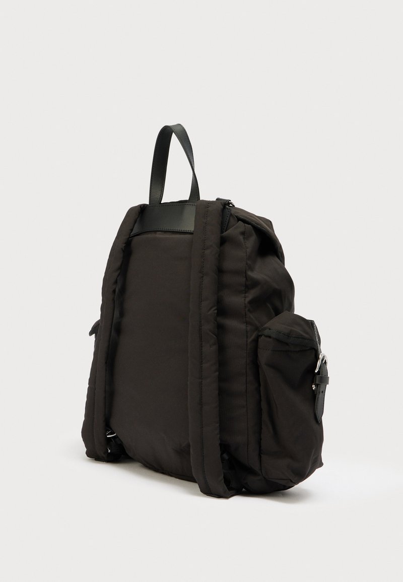 Sort polstret rygsæk med topgreb, to sidelommer og læderdetaljer. Har en glat tekstur og lynlås.