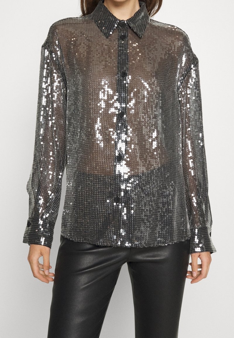 Camicia trasparente con paillettes, botton-up, colletto strutturato, bottoni neri, maniche lunghe e una texture riflettente in tonalità di grigio e argento.
