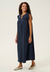 Marinblå maxikjol med volangärmar, med en V-ringning och lös passform, tillverkad i lätt tyg, i kombination med beige ballerinas.