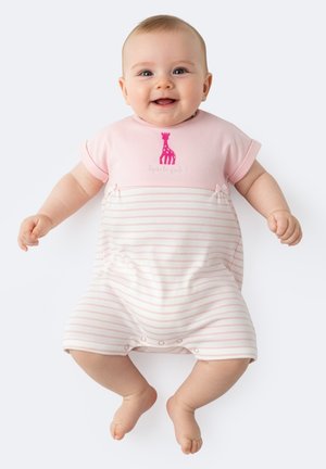 Bambino sorridente in tutina a righe rosa e bianca con stampa di giraffa, sdraiato su una superficie bianca con braccia e gambe leggermente sollevate.