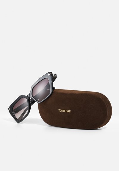 Svarta oversized solglasögon med gradientlinser, med en kantig form och detaljer i guldton. Brunt mockaskydd med präglad "TOM FORD"-logga.
