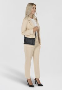 Black leather crossbody bag with embossed "Desigual" logo, rectangular shape, adjustable strap, and smooth texture.
