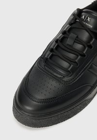 Adidași din piele neagră, cu un upper neted, vârf rotund, detalii perforate și talpă din cauciuc texturat negru. Include șireturi negre și branding.