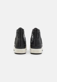 Black leather high-top sneakers with white accents, contrasting stitching, and iconic logo patches on the back. Round toe and textured sole.