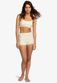 Bralet s kvetinovým vzorom a vysokým pásom šortky, vyrobený z mäkkej a elastickej látky. Obsahuje pastelové farby: ružovú, žltú a zelenú kvetinovú potlač.