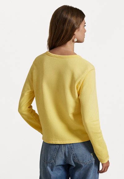 Yellow long-sleeve shirt with a crew neckline, made from soft fabric. Features a simple design with straight seams and moderate stretch.