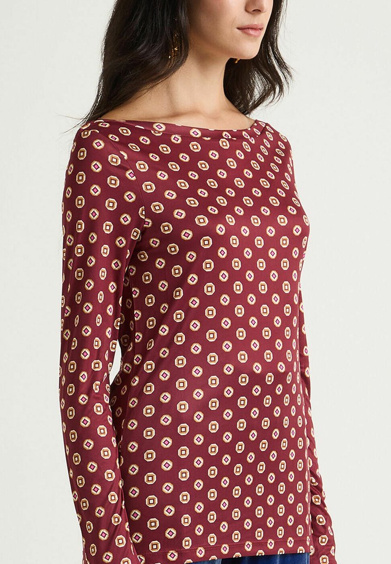 Langärmliges dunkelrotes Oberteil mit einem geometrischen Muster und kleinen cremefarbenen und rosa Akzenten, gefertigt aus weichem Stoff mit einem lockeren Schnitt.