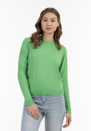 Maglione verde a maniche lunghe in morbido tessuto a maglia con scollatura rotonda e orlo a coste, indossato con jeans azzurri chiari.