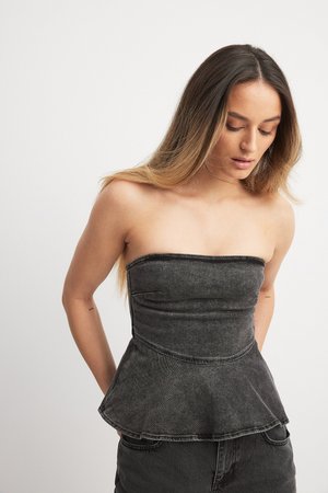 Čierna deninová top bez ramienok s peplum strihom, priliehavou časťou a vyšívaným lemom. Textúrovaná tkanina so švovými detailmi, skombinovaná s čiernymi nohavicami.
