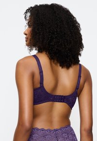 Violetti pitsi rintaliivi, jossa on kukkakuosi, säädettävät olkaimet ja kolmonen hakasuljenta takana tuen ja istuvuuden varmistamiseksi.