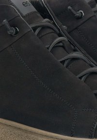 Czarne zamszowe botki za kostkę o eleganckim designie, okrągłych sznurowadłach i teksturowanej podeszwie, z subtelnymi detalami w postaci szwów.