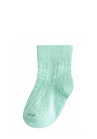 Chaussette pour bébé verte clair côtelée avec revers plié, présentée à plat sur un fond blanc.