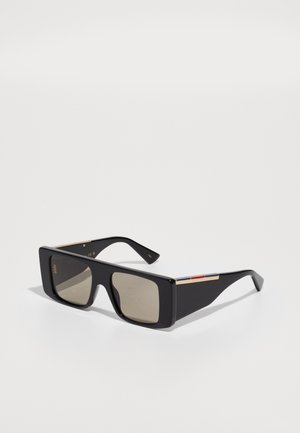 Óculos de sol retangulares pretos com lentes castanhas. Apresentam detalhes em dourado e um acento decorativo vermelho e azul nas hastes.