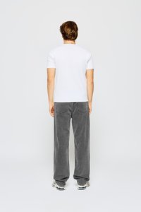 Camiseta blanca de manga corta combinada con pantalones vaqueros grises anchos, con un diseño sencillo y una textura de tela suave, visible desde la parte de atrás.