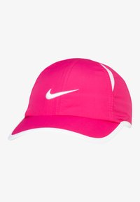 Rosa keps av lätt tyg med en vit Nike-logotyp, vita detaljer på skärmen och en strukturerad design med synliga sömmar.