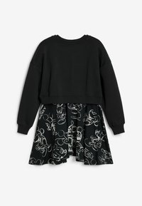 Schwarzes, kurzes Sweatshirt, kombiniert mit einem schwarzen Rock, der mit weißen Skizzen von Comicfiguren gestaltet ist. Weicher Stoff mit gerippten Bündchen.