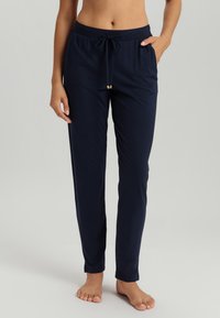 Marineblauwe loungebroek van zacht materiaal, met een elastische tailleband voorzien van een trekkoord en gouden accenten aan de uiteinden, nauwsluitend bij de enkels.