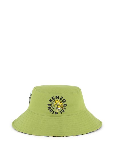 Chapeau seau vert en coton, présentant un graphique circulaire noir avec un tigre jaune et le texte "KENZO PARIS 1970". Design à bord évasé.