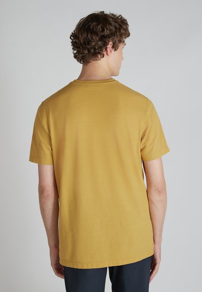 T-shirt a maniche corte di colore giallo senape, realizzato in tessuto morbido, con collo rotondo e vestibilità comoda, con cuciture pulite e senza grafiche visibili.