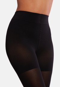 Leggings neri a vita alta con un design testurizzato, dotati di una fascia in vita liscia e un pannello trasparente nella parte inferiore delle gambe.