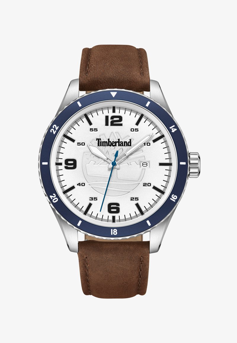 Hodinky Timberland se stříbrným pouzdrem, bílým ciferníkem, námořnickým rámečkem, hnědým koženým řemínkem a modrým akcentem na sekundové ručičce. Černé hodinové indexy.