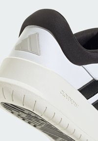 Sneaker bianca con accenti neri, tomaia testurizzata, suola in gomma e marchio Cloudfoam sul tallone. Presenta una superficie liscia e una forma arrotondata.