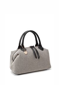 Borsa a mano in tessuto a righe bianche e nere con dettagli in pelle nera, doppi manici e una catena decorativa dorata con un'etichetta circolare.